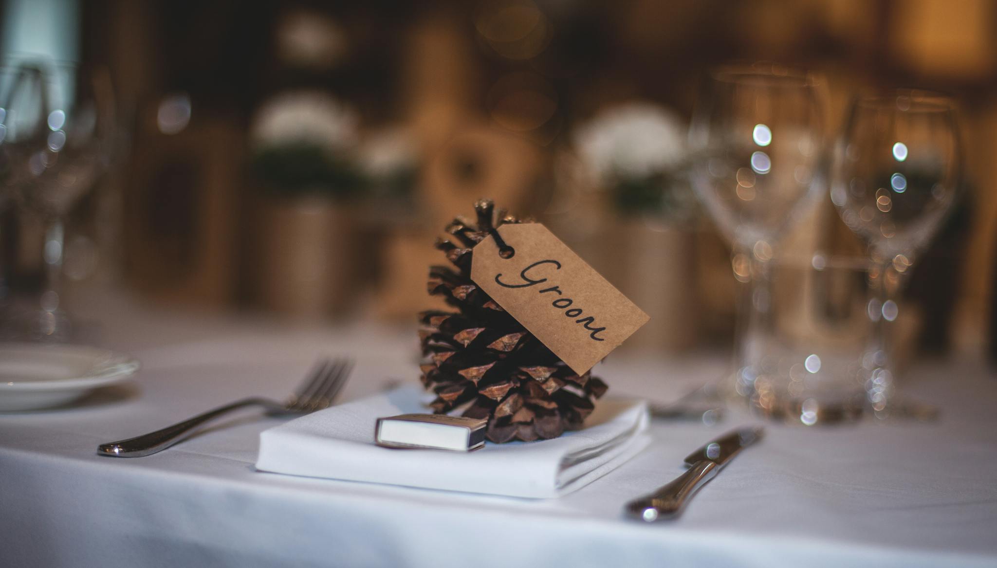 A beautifully arranged wedding table featuring a pine cone with a 'Groom' tag, adding rustic charm.