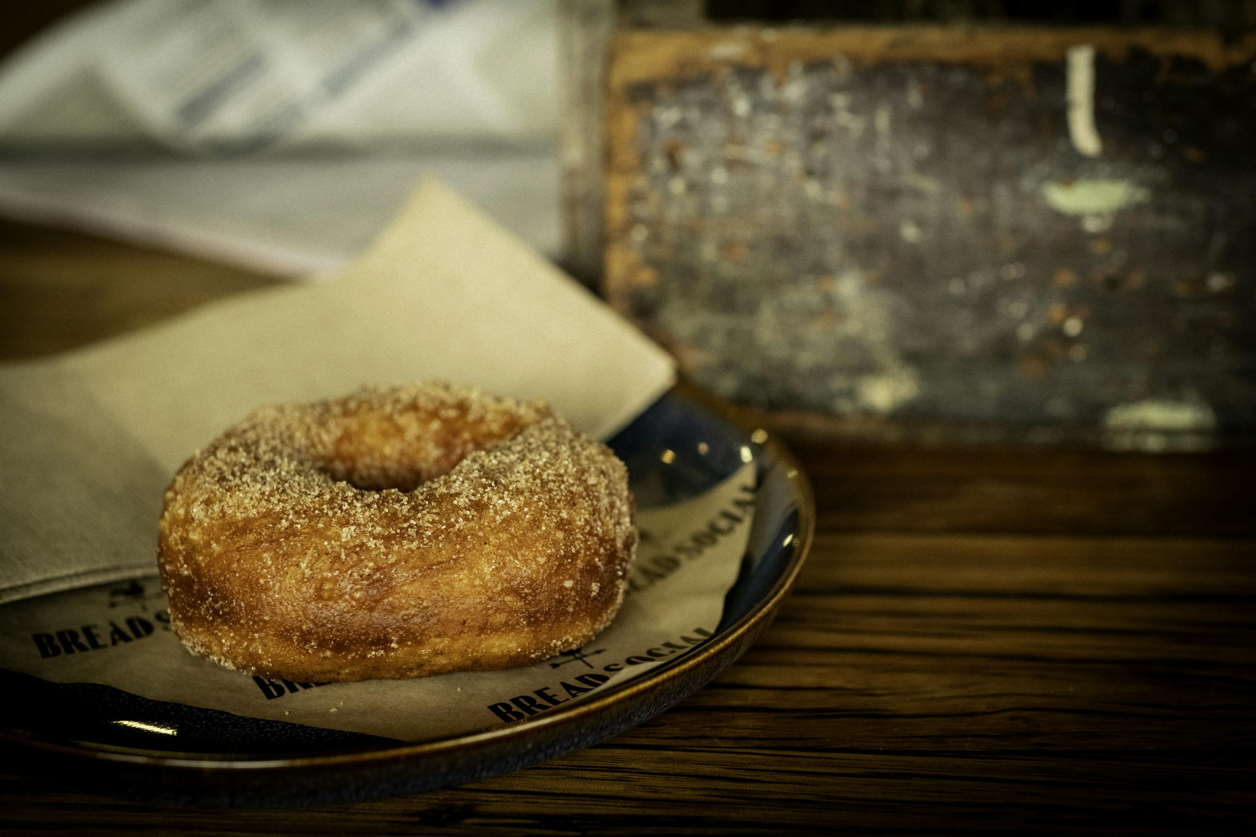 A delicious cinnamon sugar donut on a rustic plate in a cozy café setting.