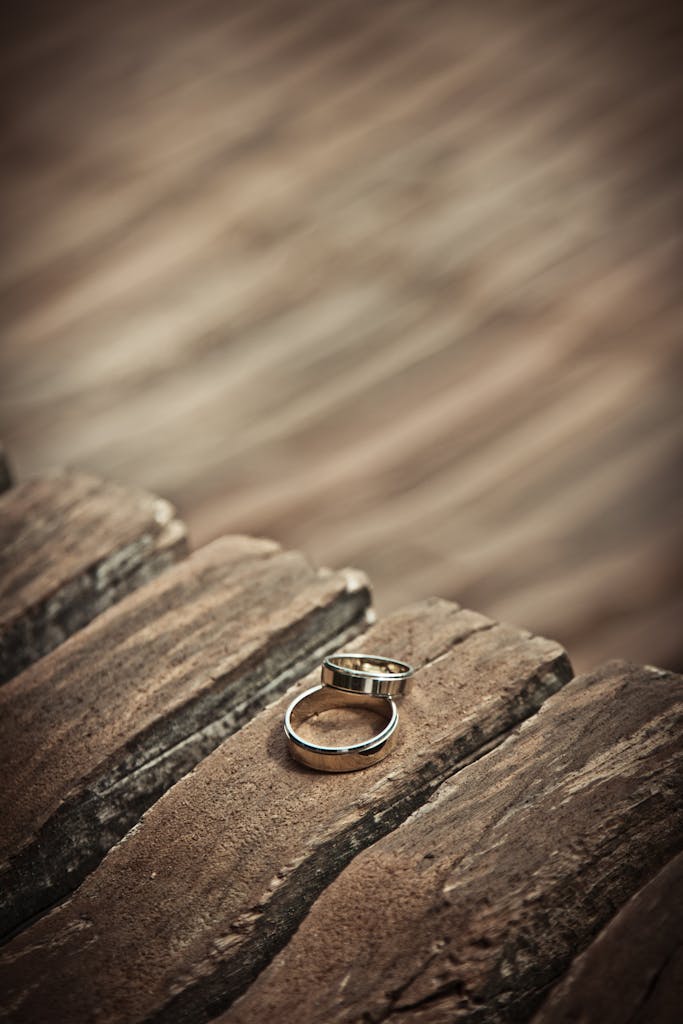 Close-up of elegant silver wedding rings on a rustic wooden surface, symbolizing love and unity.