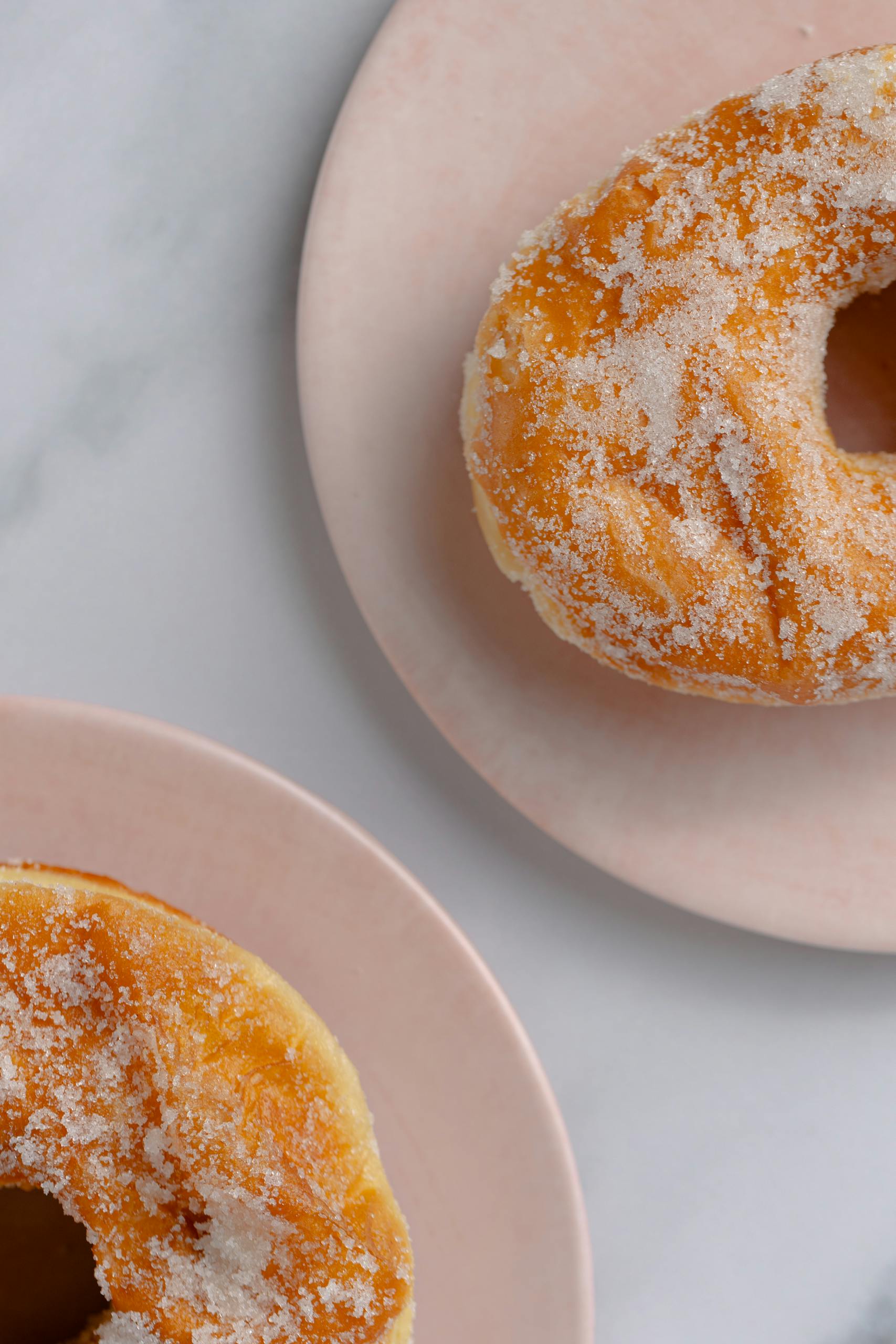 Close-up of sugar-coated donuts on pink plates, perfect for sweet treats and dessert photography.
